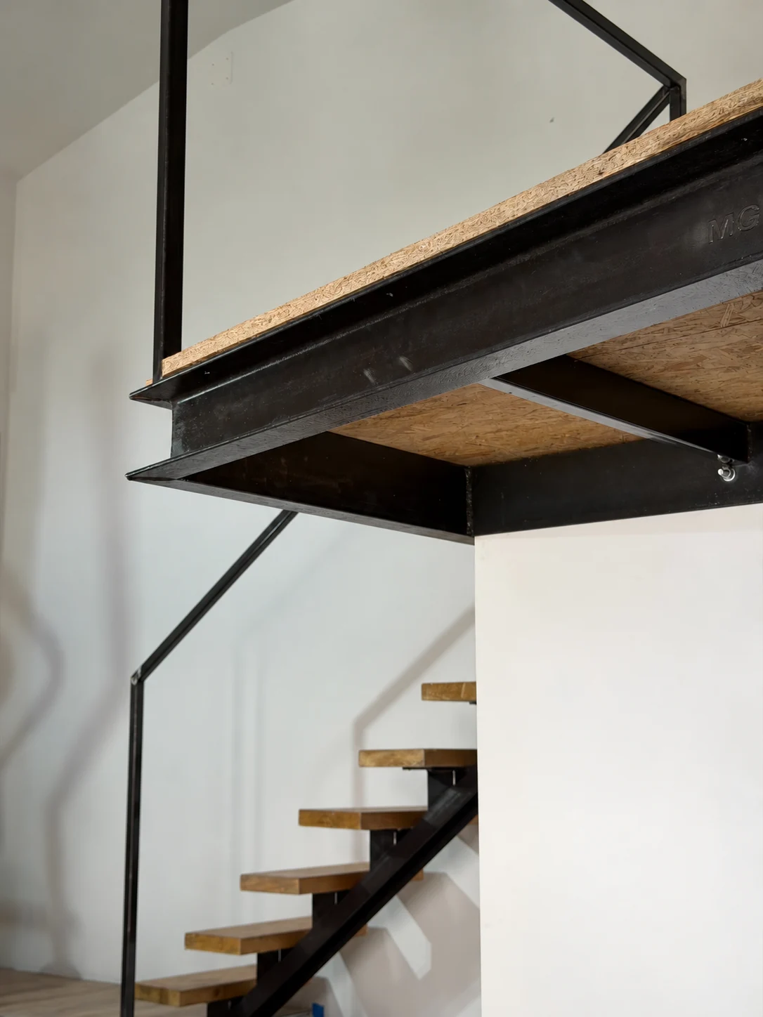 Escalier métallique avec marches en bois sous une mezzanine